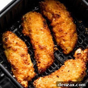 Crispy Air Fryer Chicken Tenders Recipe 8 four breaded and cooked chicken tenders arranged inside a black air fryer basket.