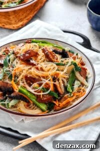 Japchae (Korean glass noodle stir fry) in a serving bowl, with chopsticks.