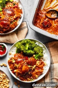 Peanut chicken served with broccoli over rice. A baking dish of the chicken is nearby on the table, along with garnishes and more plates.