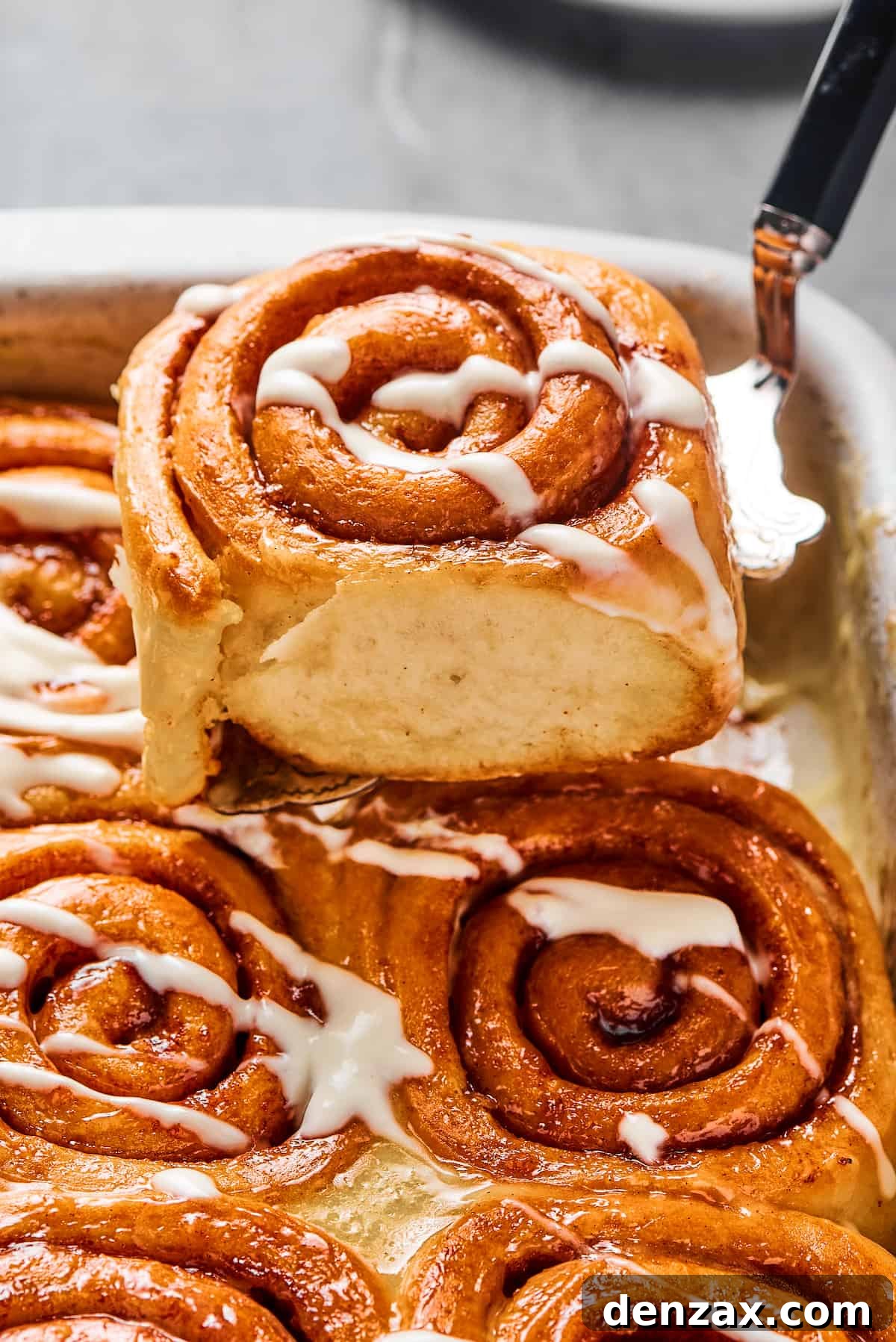 Soft, sticky Cinnamon Rolls from Scratch are simple to make and utterly addictive to eat! A cinnamon bun lifted from a pan, to show the texture of the torn side of the roll.