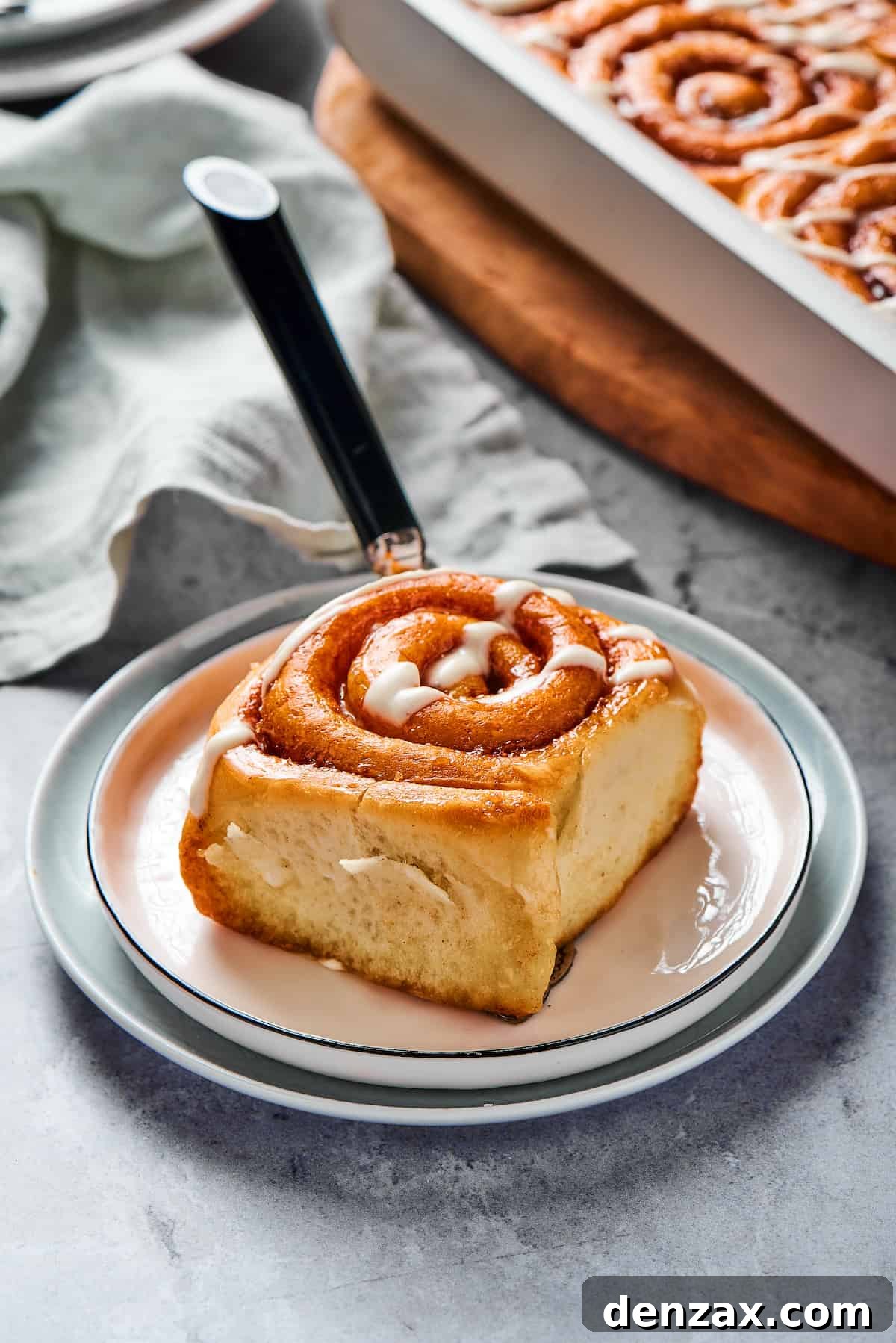 Homemade Cinnamon Rolls: Soft, Fluffy Recipe from Scratch 12 A single sticky roll on a small plate, with a fork and a cloth napkin.