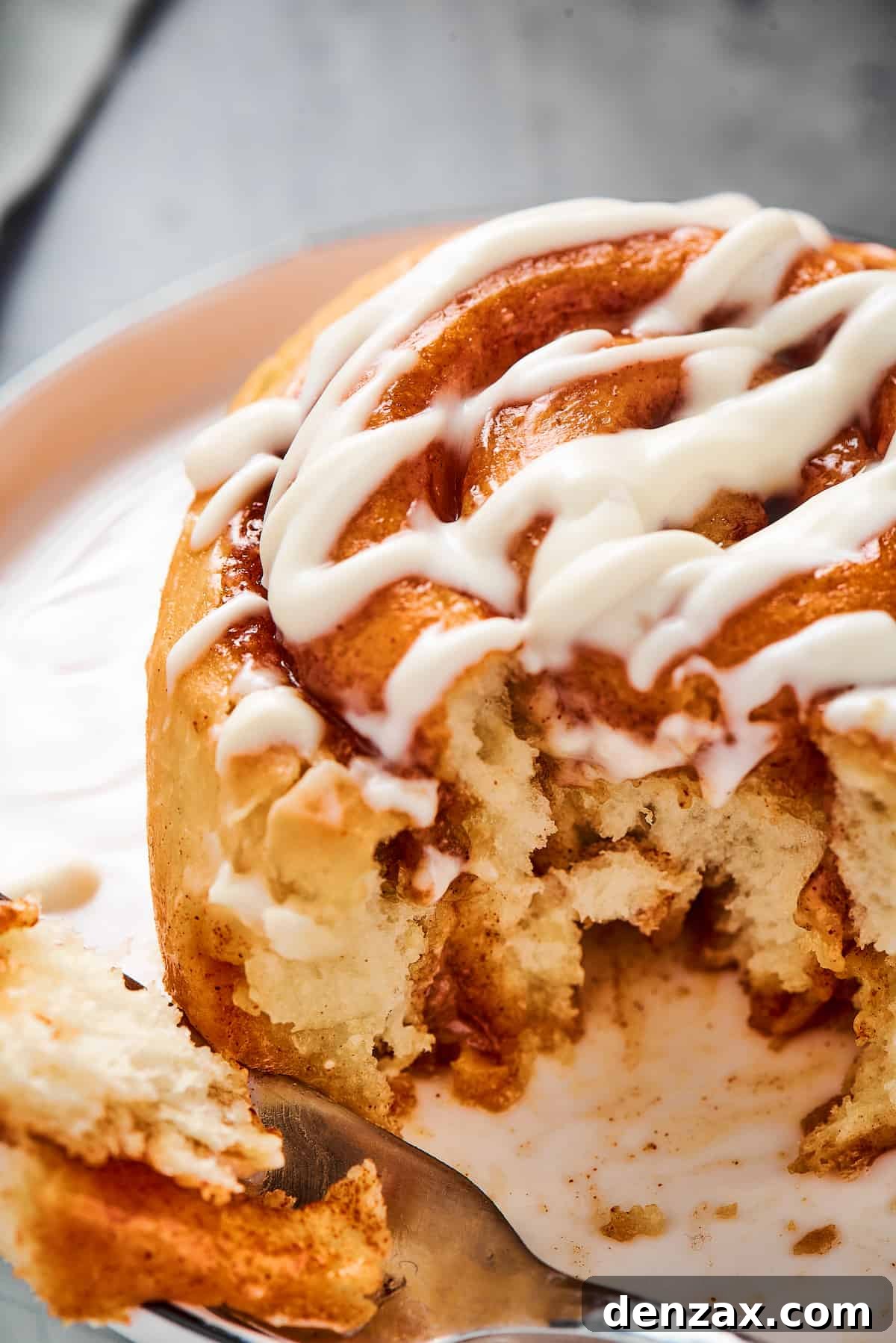 Homemade Cinnamon Rolls: Soft, Fluffy Recipe from Scratch 14 A fresh cinnamon roll with a bite taken from it, on a small plate.