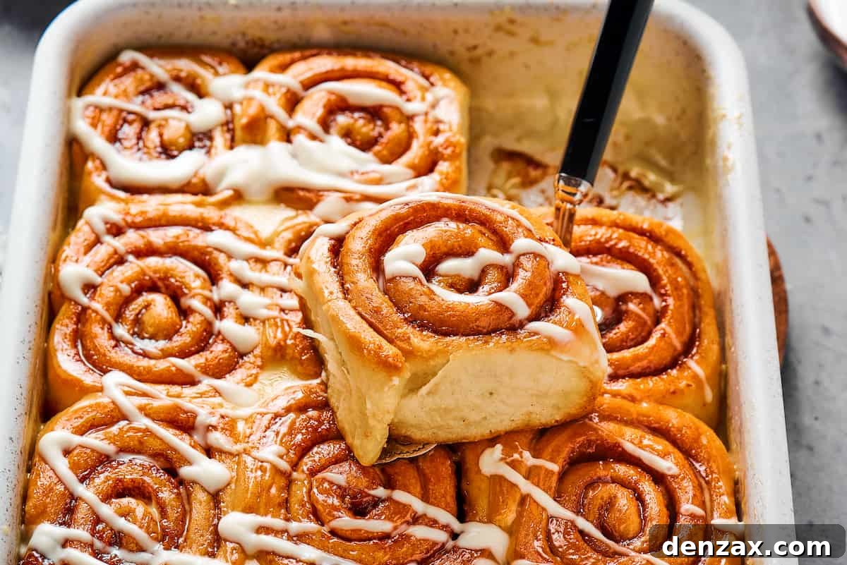 Homemade Cinnamon Rolls: Soft, Fluffy Recipe from Scratch 15 One sticky roll iced with a drizzle of glaze, sitting on the pan of rolls.