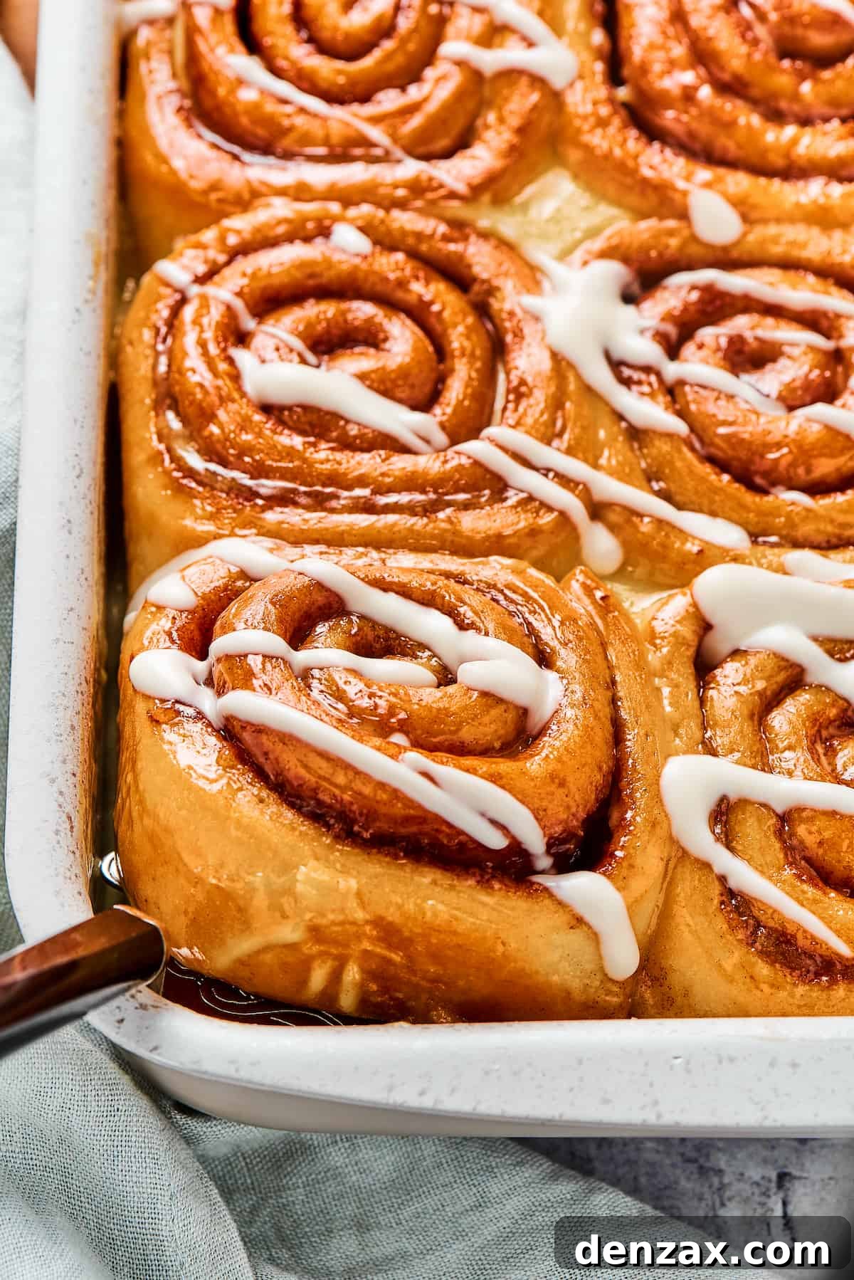 Homemade Cinnamon Rolls: Soft, Fluffy Recipe from Scratch 3 A pan of sticky homemade cinnamon buns. One is being lifted from the corner of the pan with a metal spatula.