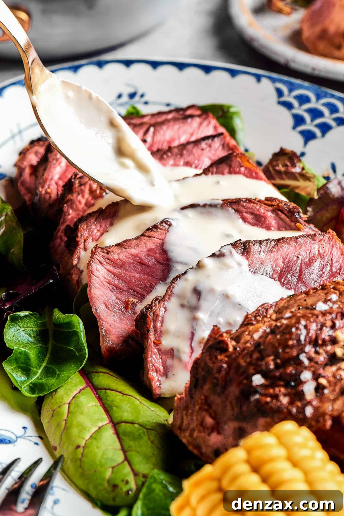 Steak slices with creamy sauce being spooned over the top.
