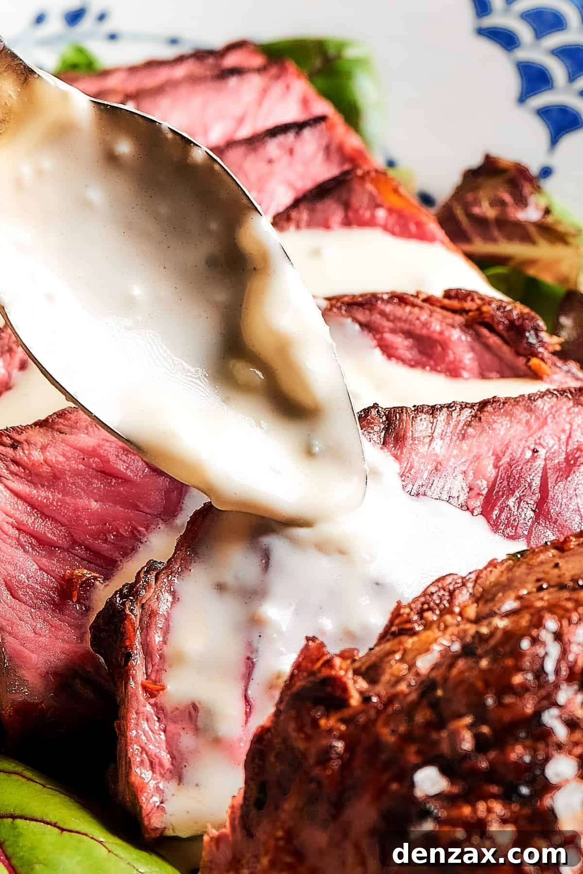 Steak slices with creamy sauce being spooned over the top.
