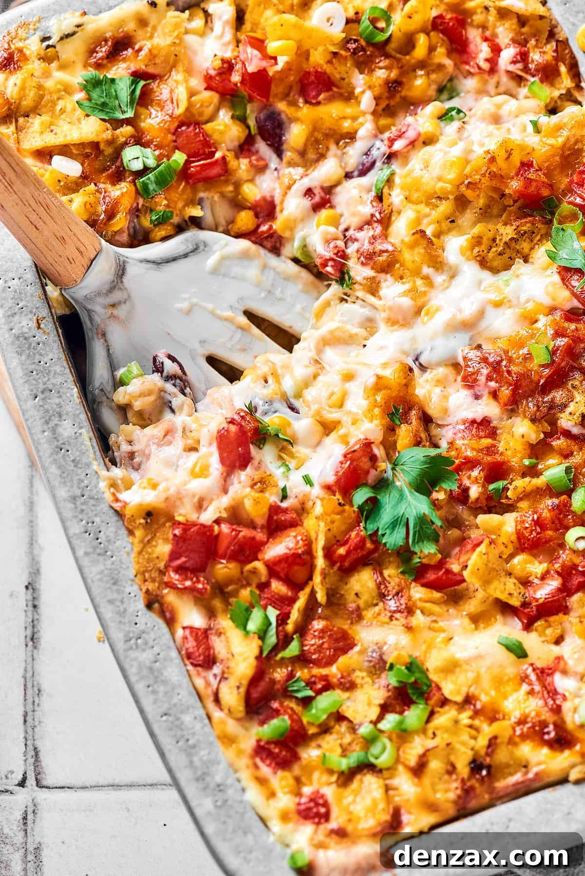 A serving utensil in a large baking pan of cheesy chicken bake.