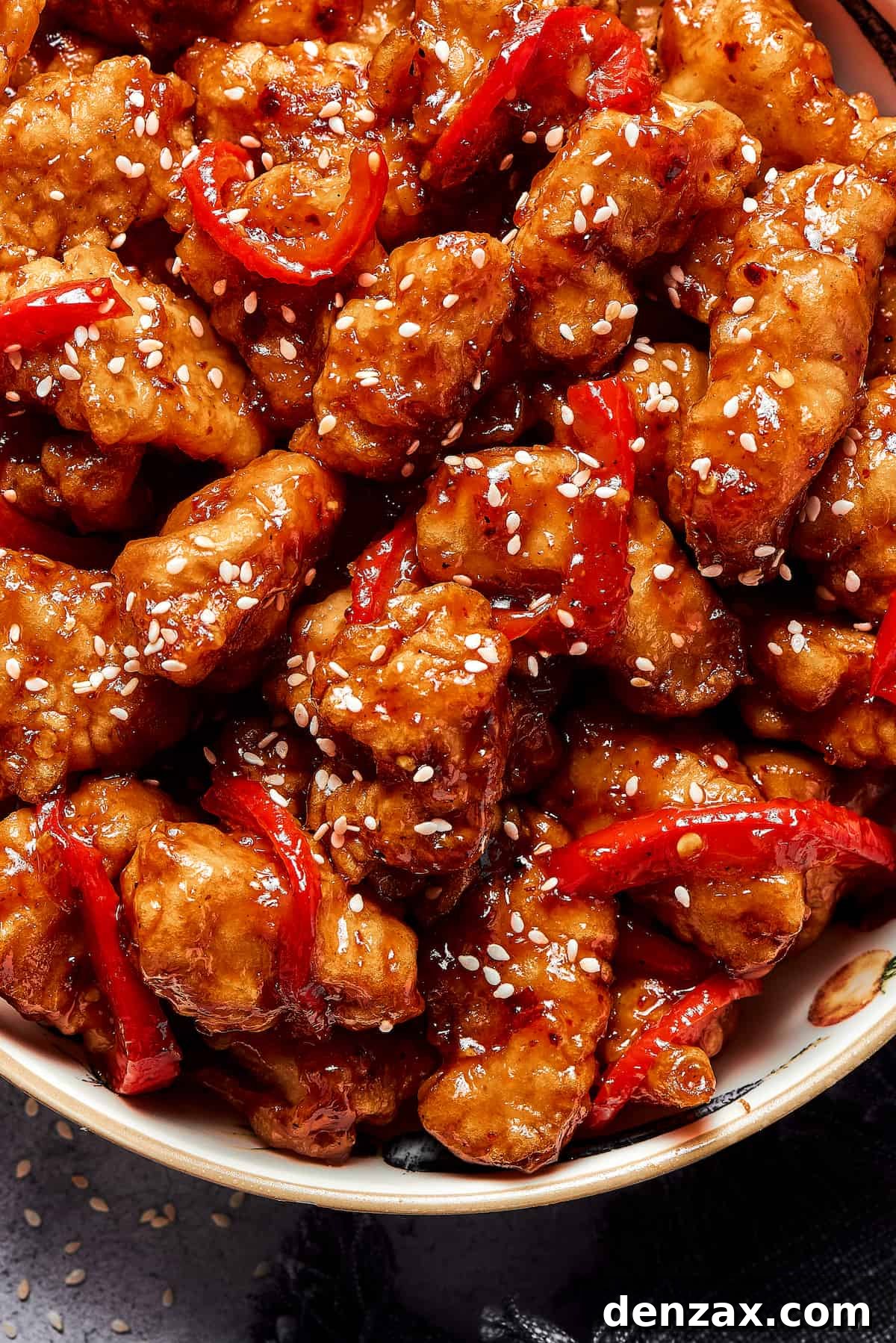 Overhead shot of saucy chicken pieces, garnished with sesame seeds.