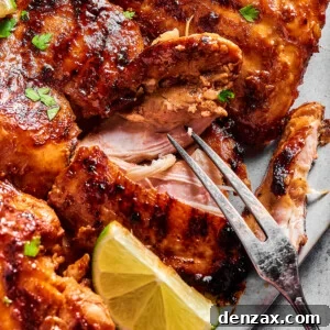 A platter of grilled chicken, with one piece being pulled apart by a grilling fork to show the texture of the interior.