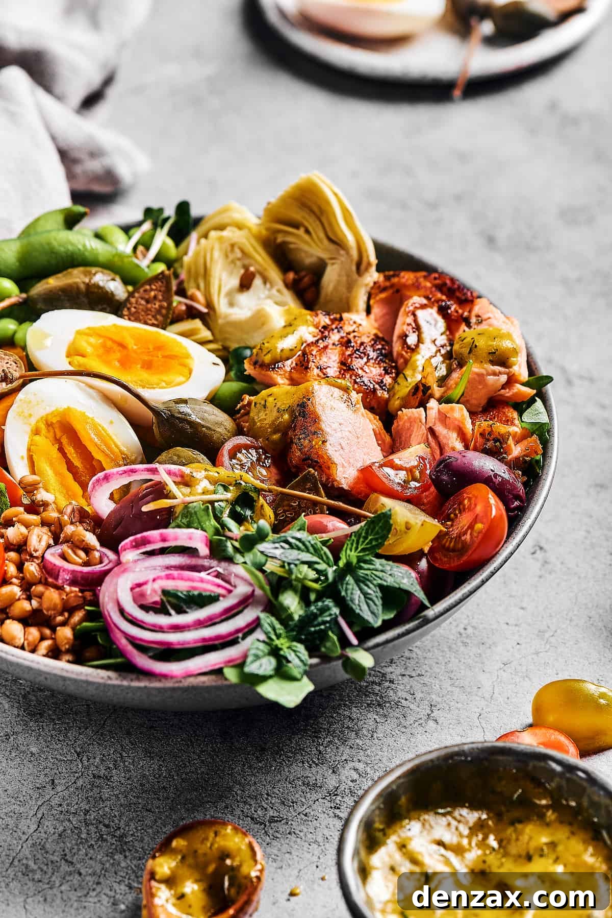 A large salad with a halved hard-cooked egg, artichoke hearts, salmon, and other ingredients.