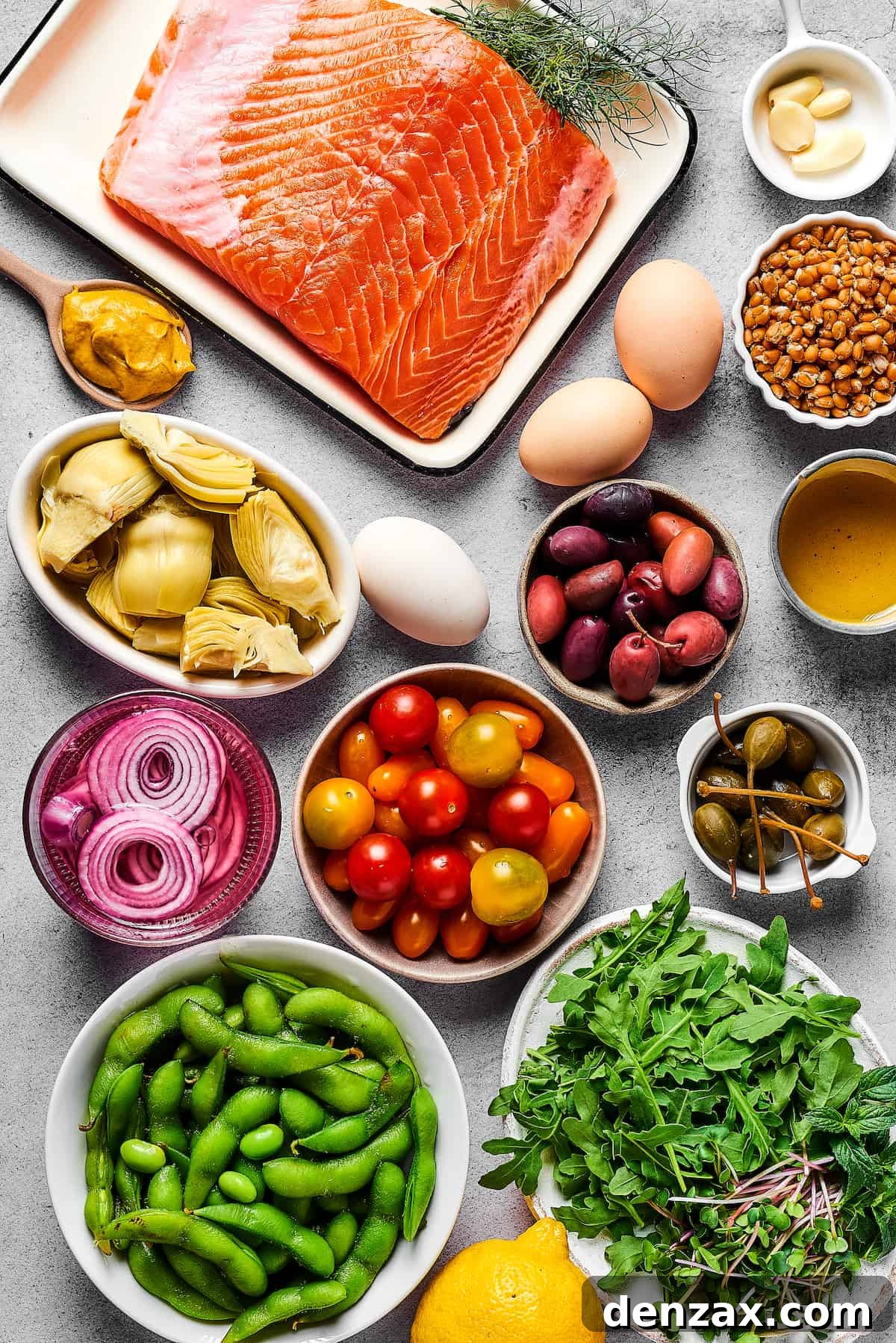 From top left: Salmon, garlic, dijon mustard, eggs, cooked grain, artichoke hearts, kalamata olives, olive oil, pickled red onions, tomatoes, capers, edamame, lemon, arugula.