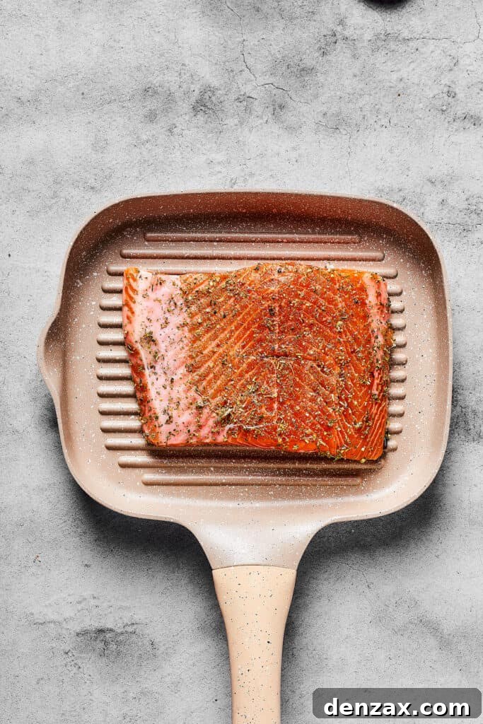 Seasoned raw salmon on a grill pan.