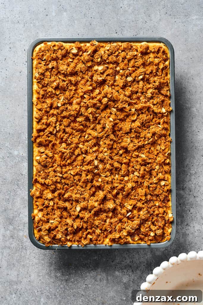 A baking dish of unbaked pumpkin bars, topped with streusel.