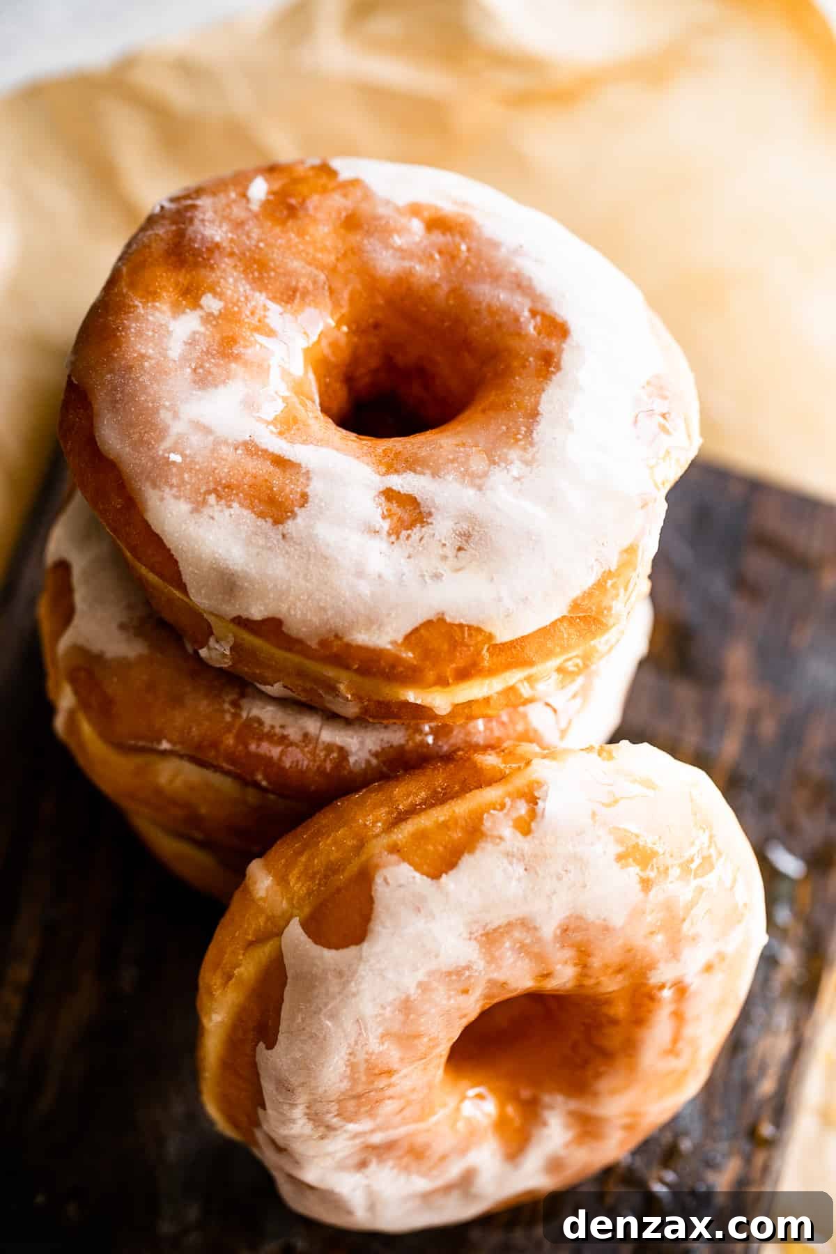 Maple-Glazed Baked Apple Cider Doughnuts for Fall Treats 7 overhead shot of stacked up baked donuts set on a brown backdrop.