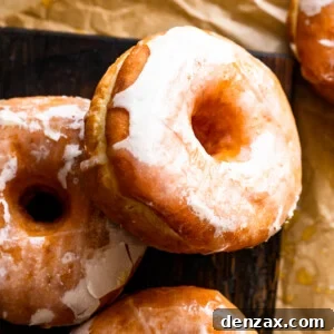 Maple-Glazed Baked Apple Cider Doughnuts for Fall Treats 8 apple cider up close photo of maple glazed doughnuts resting on a wooden board.
