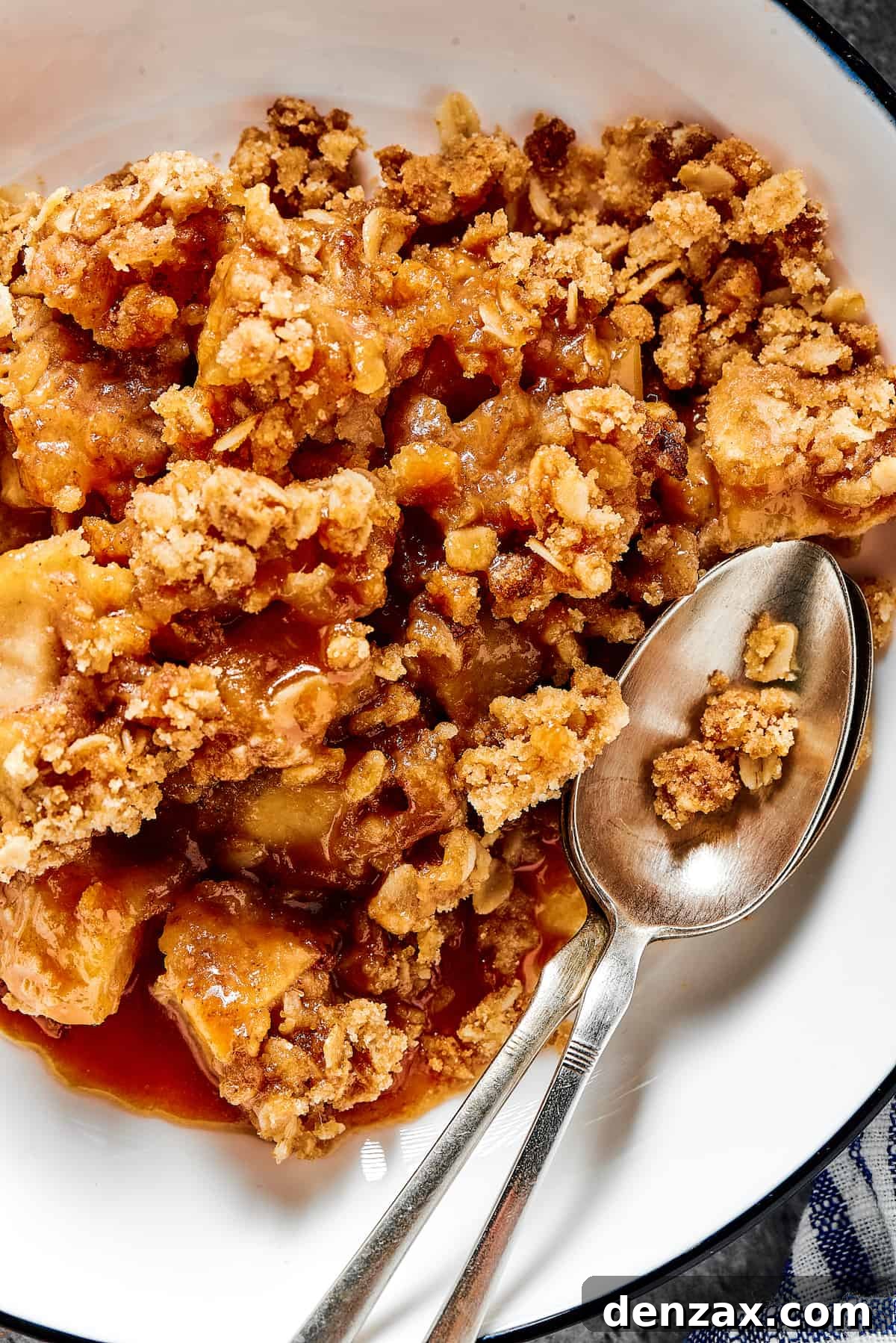 Close-up shot of apple crisp in a dessert bowl, with a spoon.
