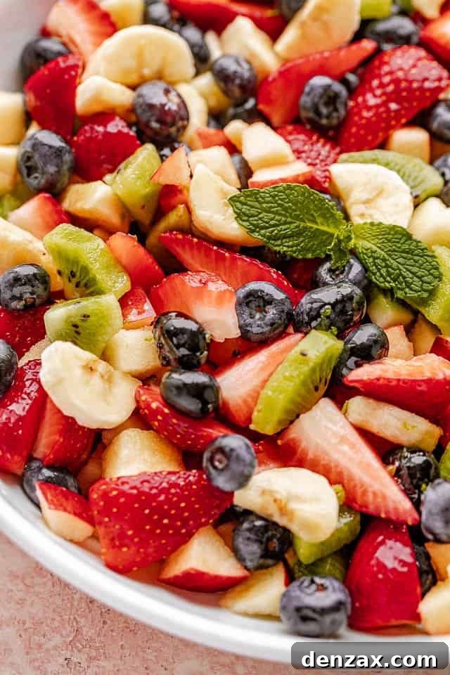 Fresh fruit salad in a bowl garnished with fresh mint leaves.