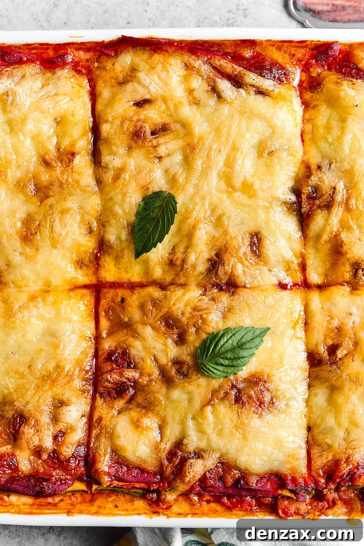 Close-up shot of a pan of baked lasagna, cut into large squares.
