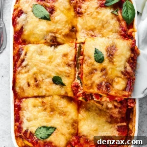 zucchini lasagna being lifted out of a white rectangular baking dish.