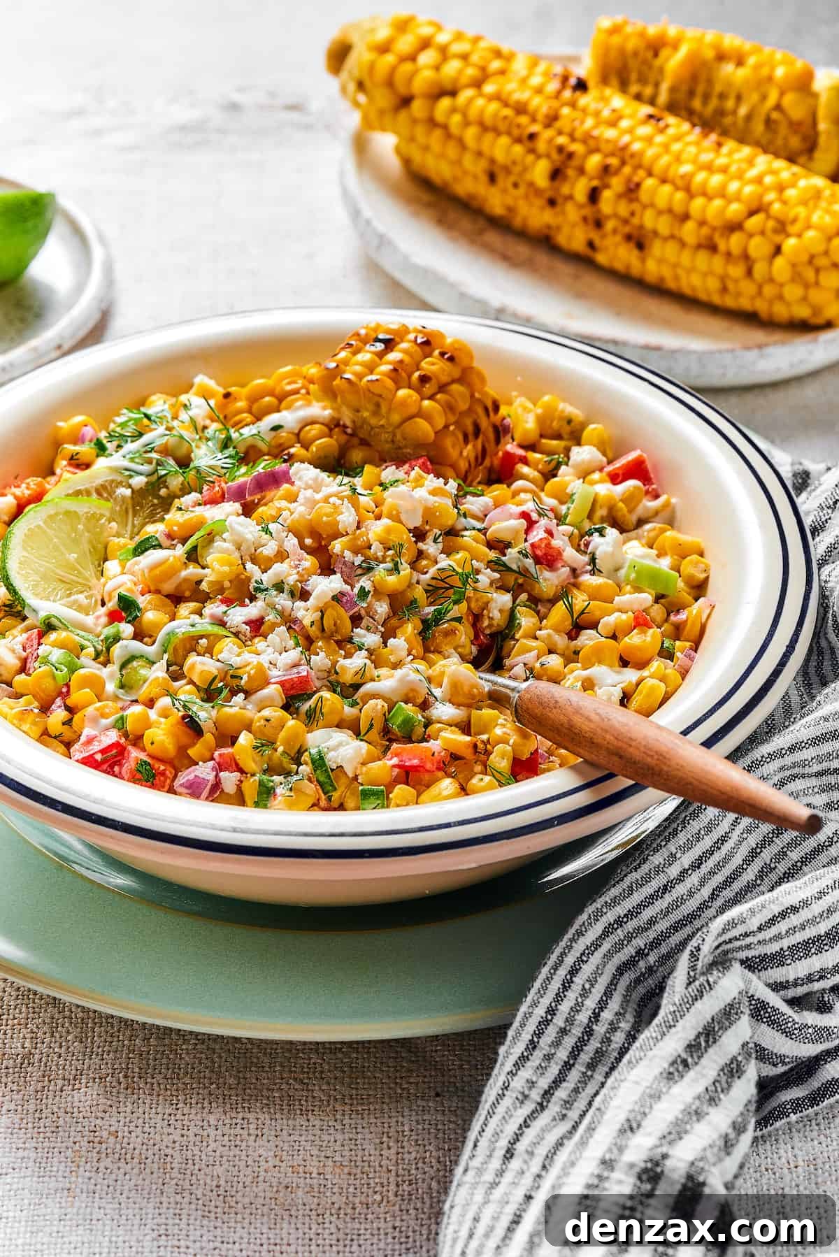 Elote salad in a bowl with a wooden-handled spoon.