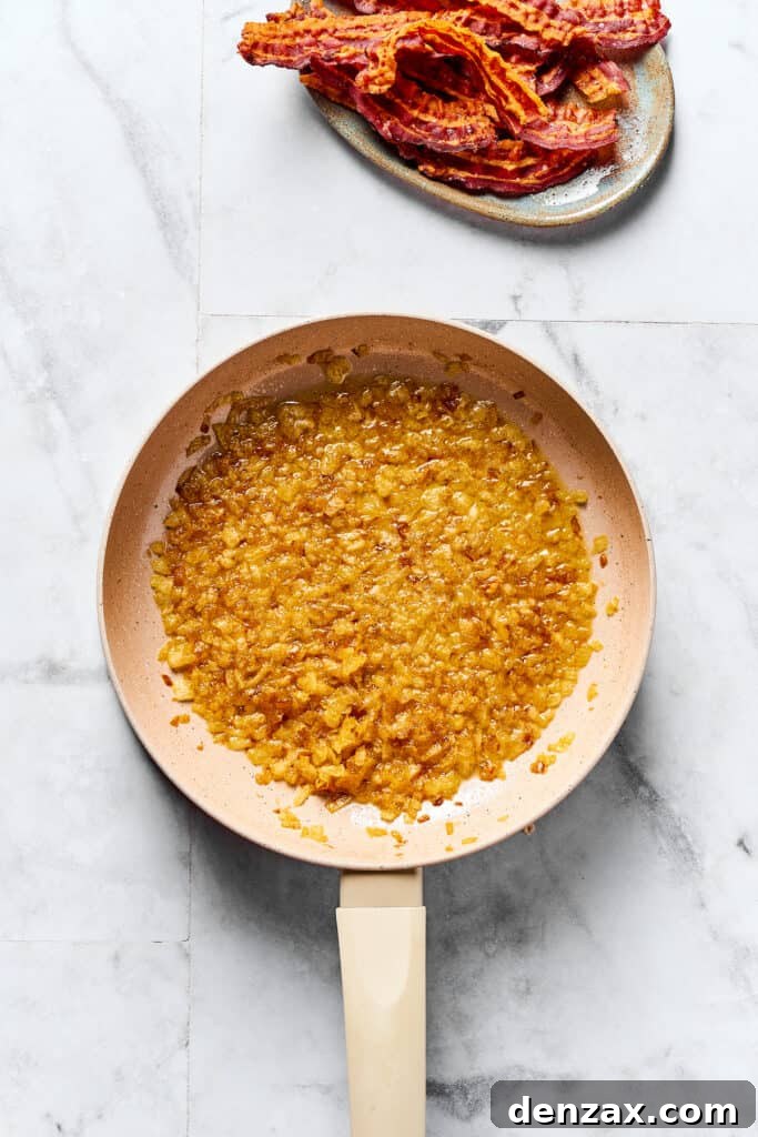 Caramelized onions and butter in a skillet. A plate of cooked bacon is nearby on the work surface.