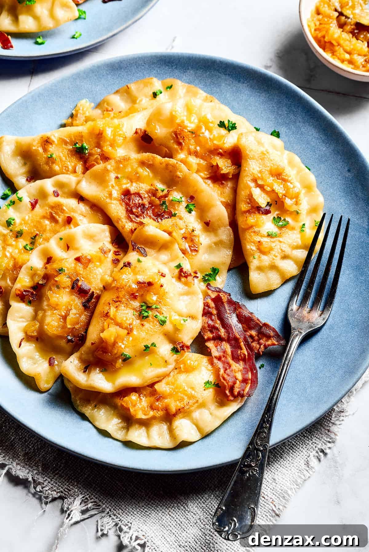 Homemade potato-filled dumplings on a blue plate with a fork.