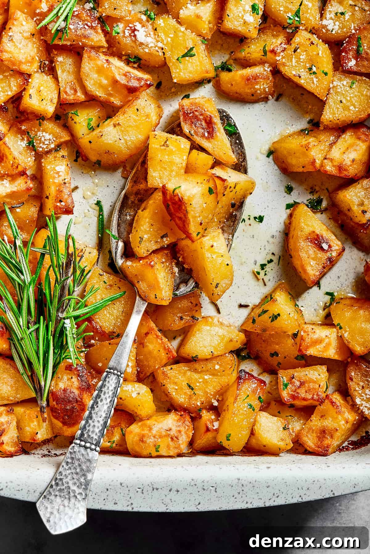 Overhead shot of seasoned baked potato chunks in a baking dish.