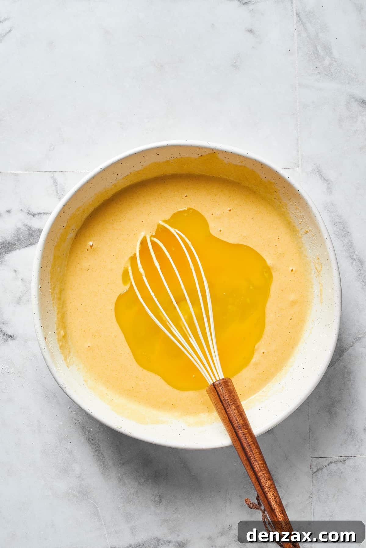 Making a well in dry ingredients using a whisk.