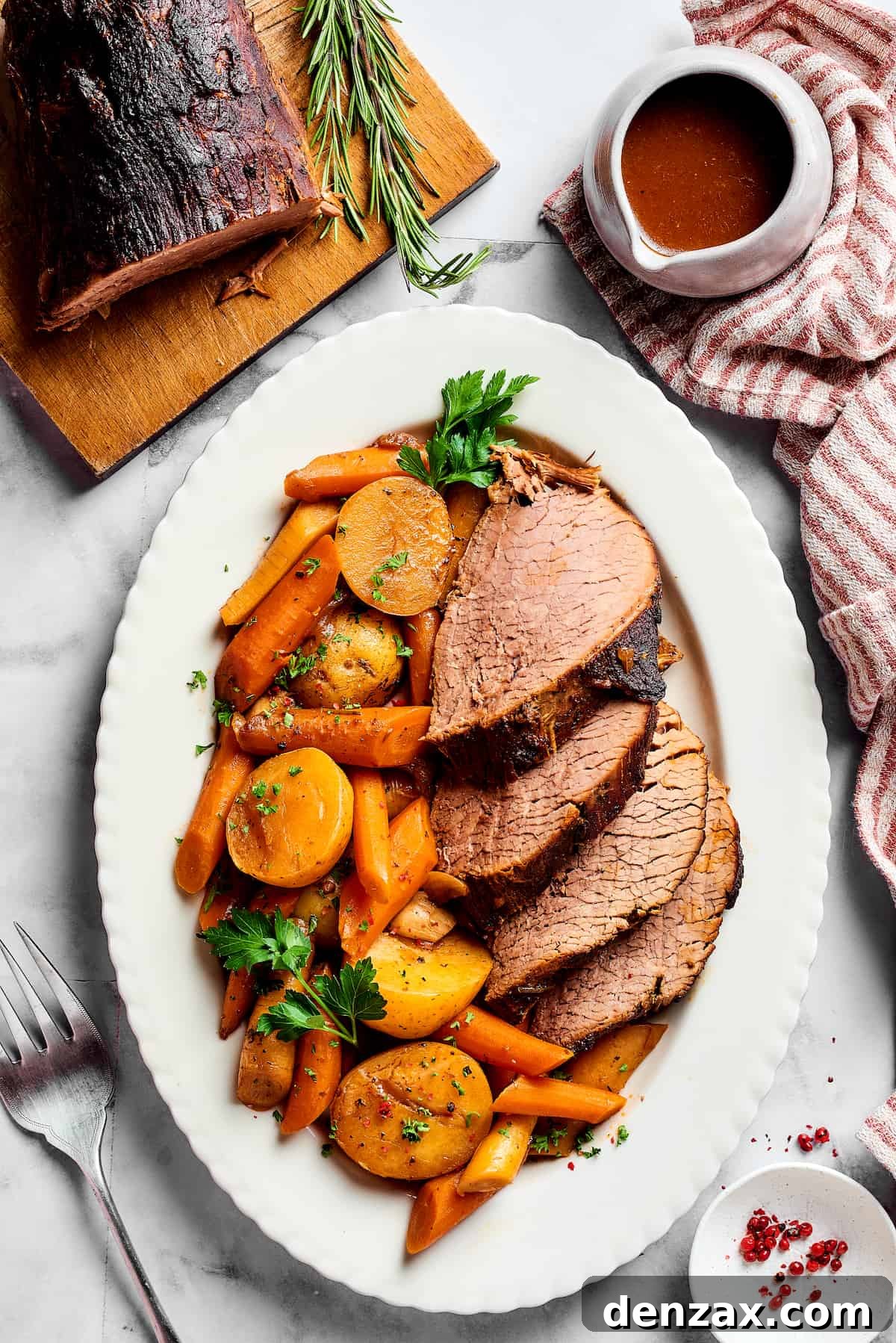 Sliced pot roast with vegetables on an oval platter.