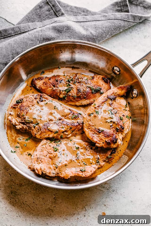 top view of four chicken breasts in a skillet with creamy balsamic sauce