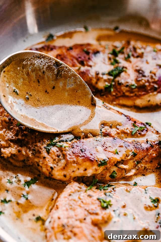 spooning creamy balsamic sauce over chicken