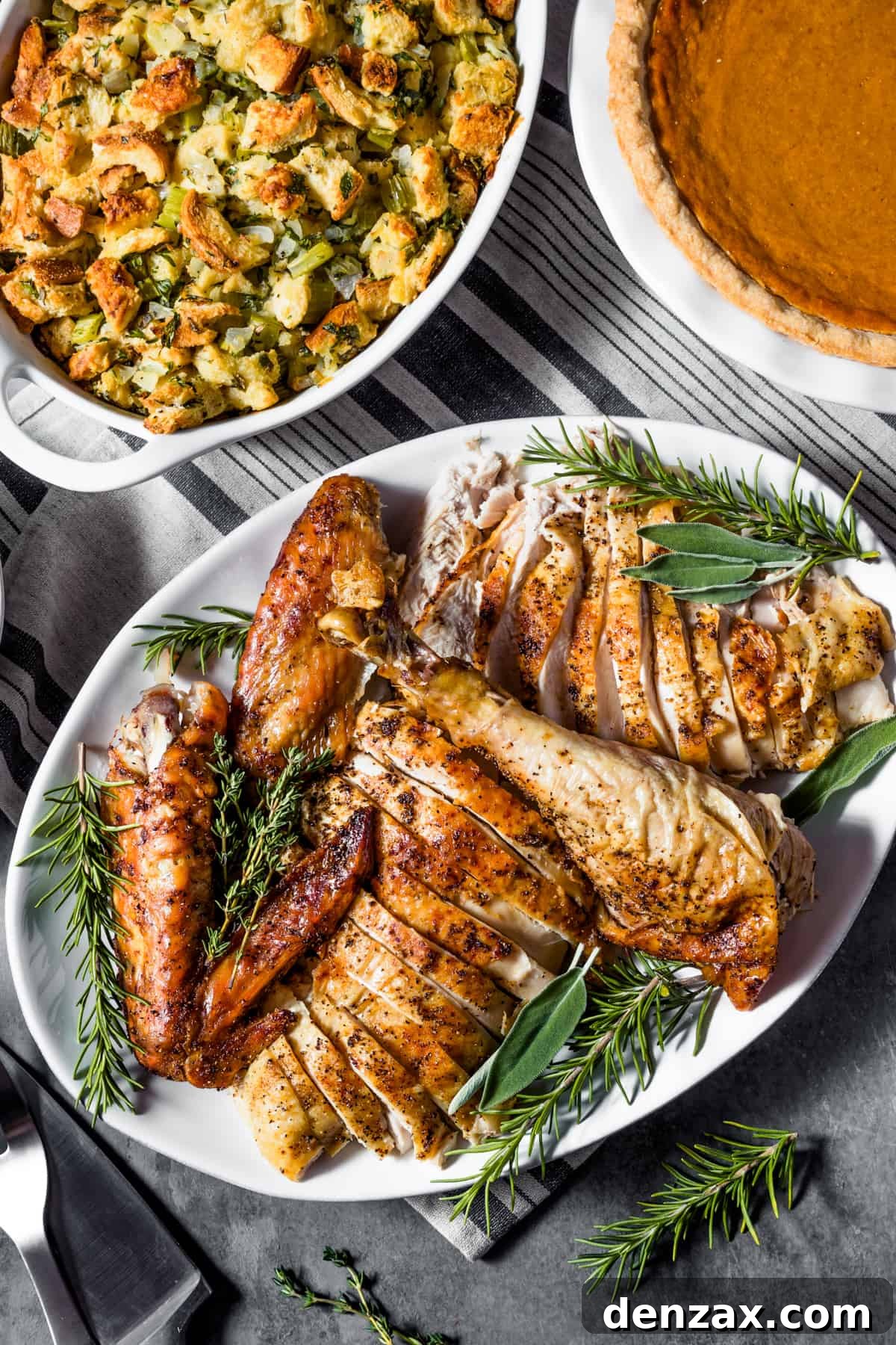 overhead shot of a cut up turkey served on a white oval platter and garnished with fresh herbs.
