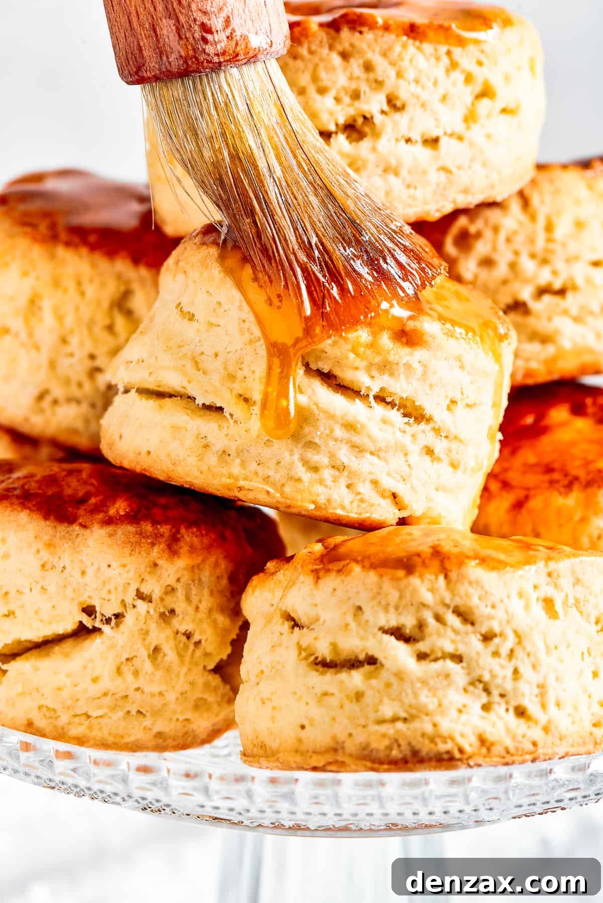 Brushing maple syrup on top of biscuits.