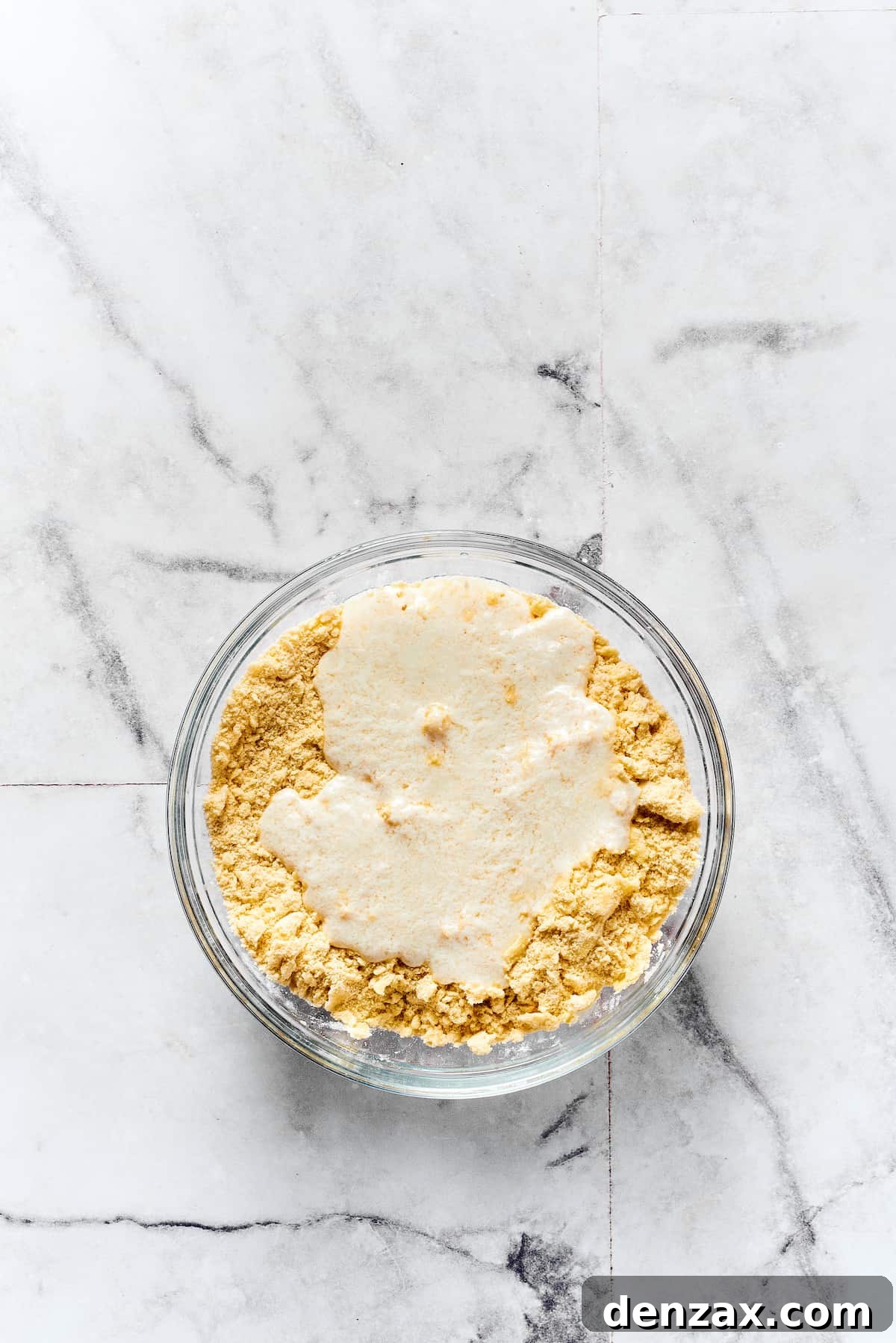 Buttermilk being mixed into biscuit dough.