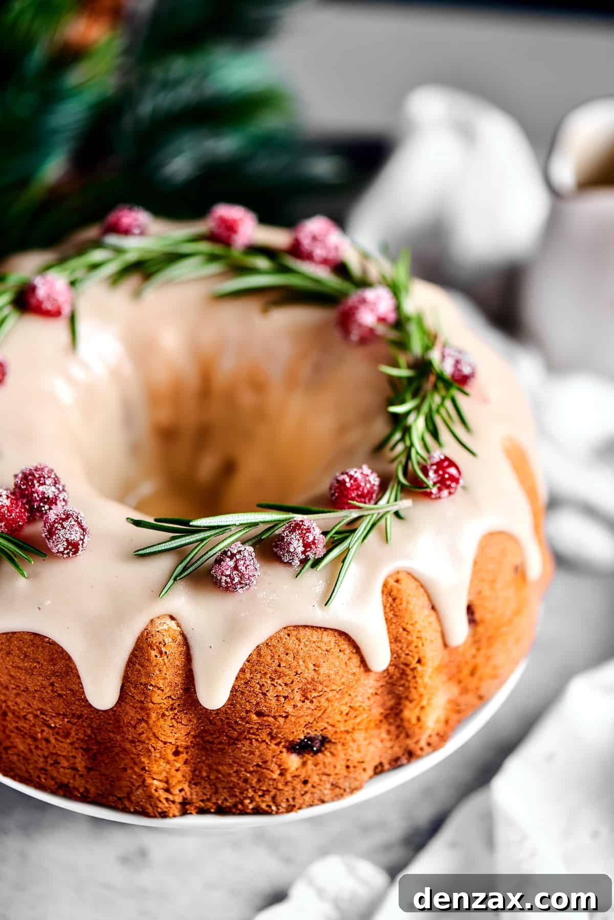 Overhead shot of a Bundt cake garnished with rosemary and sugared cranberries.