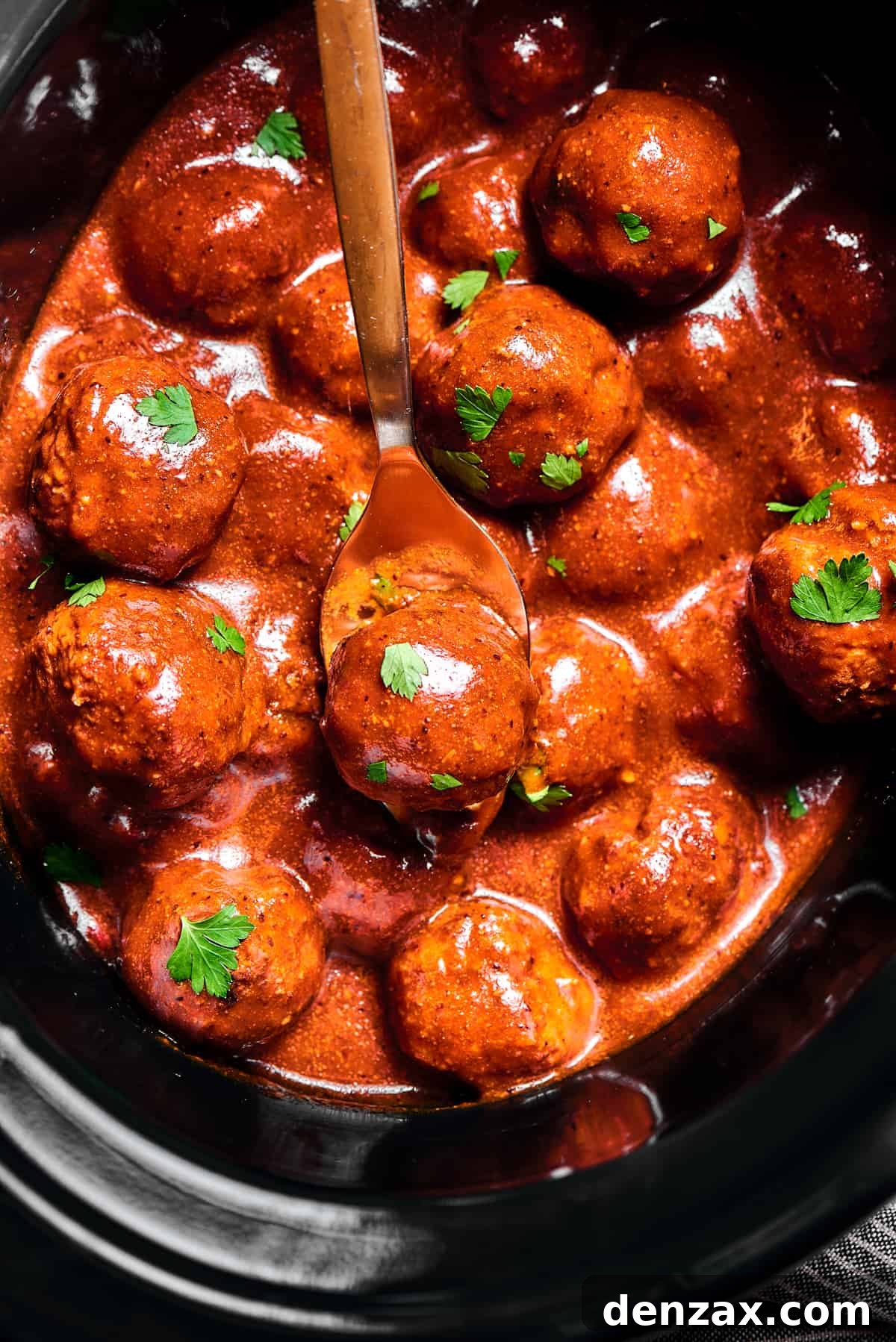 slow cooker Meatballs in sauce, sprinkled with parsley.