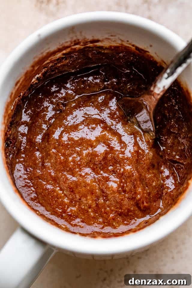 Stirring through a chocolate batter inside a mug.