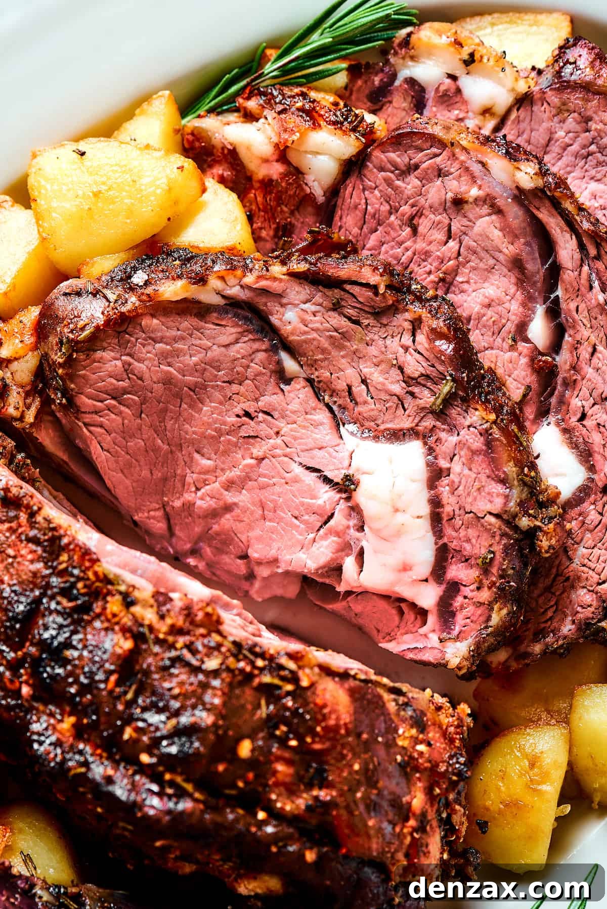 Close-up shot of prime rib, sliced and garnished with herbs.