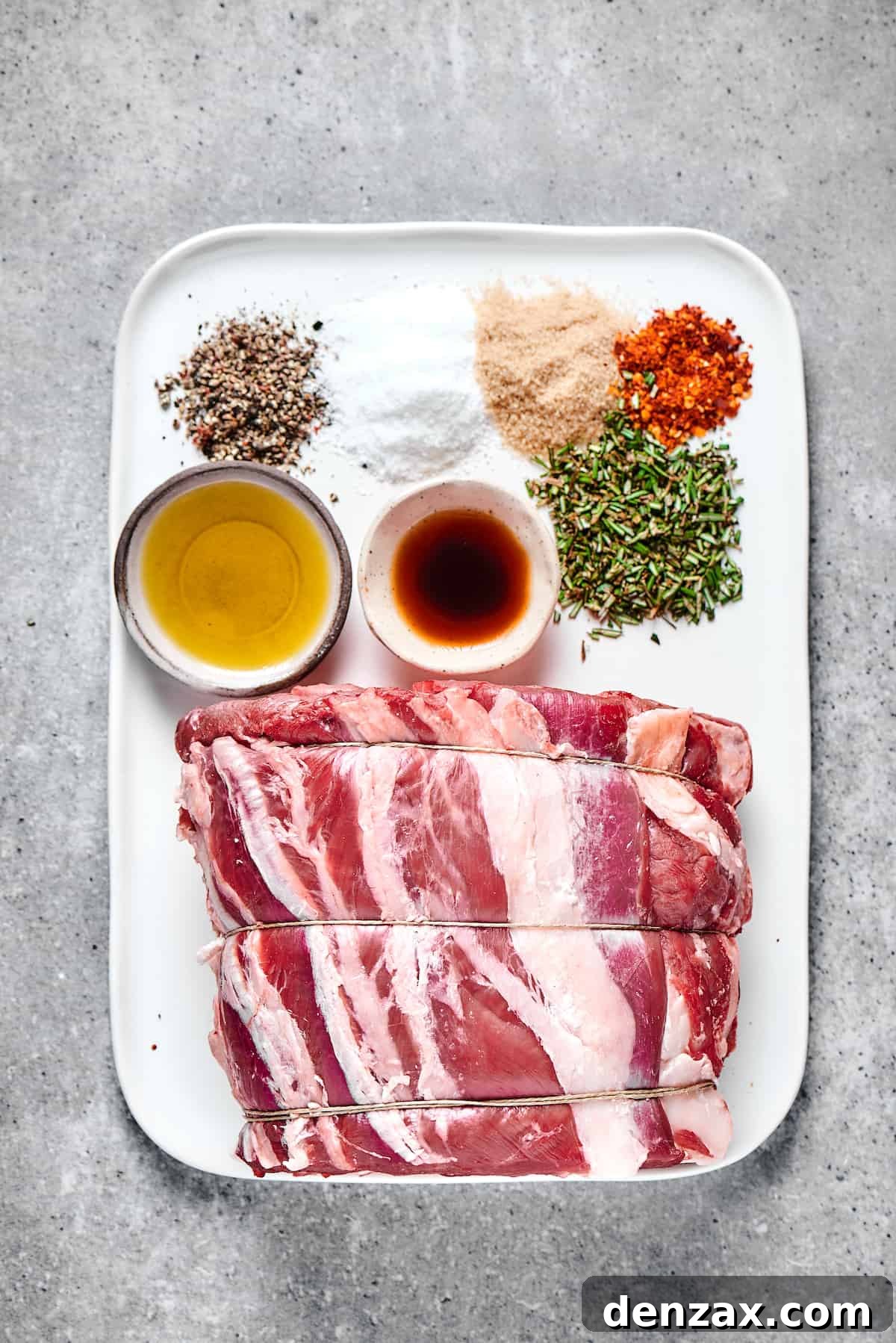 Seasonings, oil, worcestershire sauce, and a tied prime rib roast on an enamel tray.