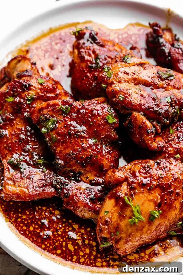 chicken thighs on a white plate topped with cajun flavored sauce