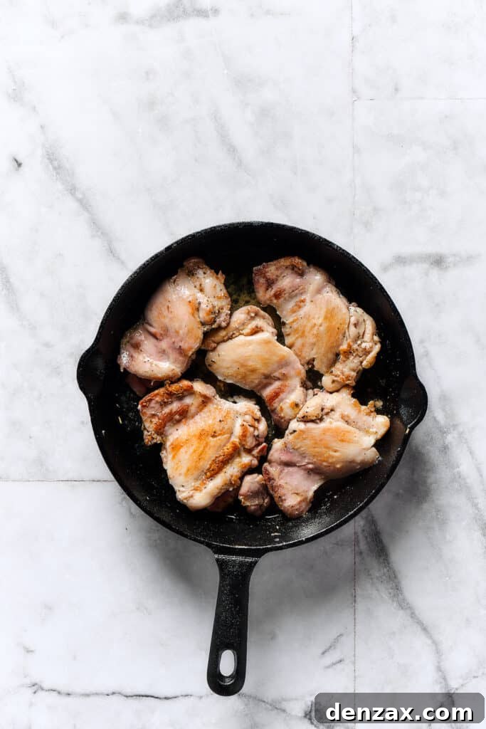 Chicken thighs browning in a skillet.