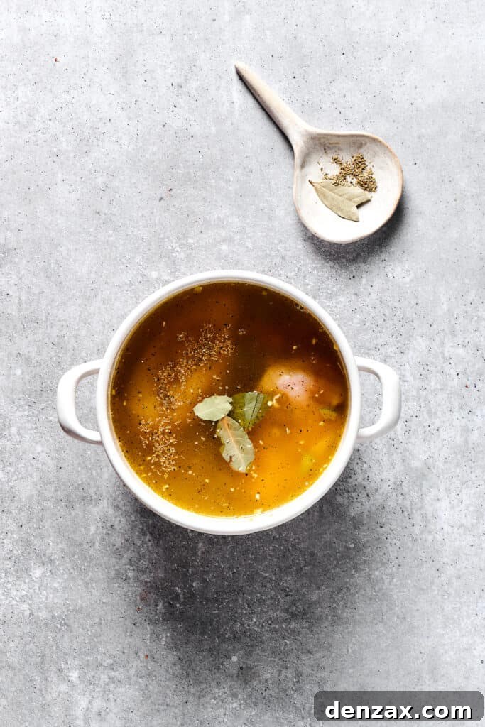 Broth and herbs added to a soup pot.