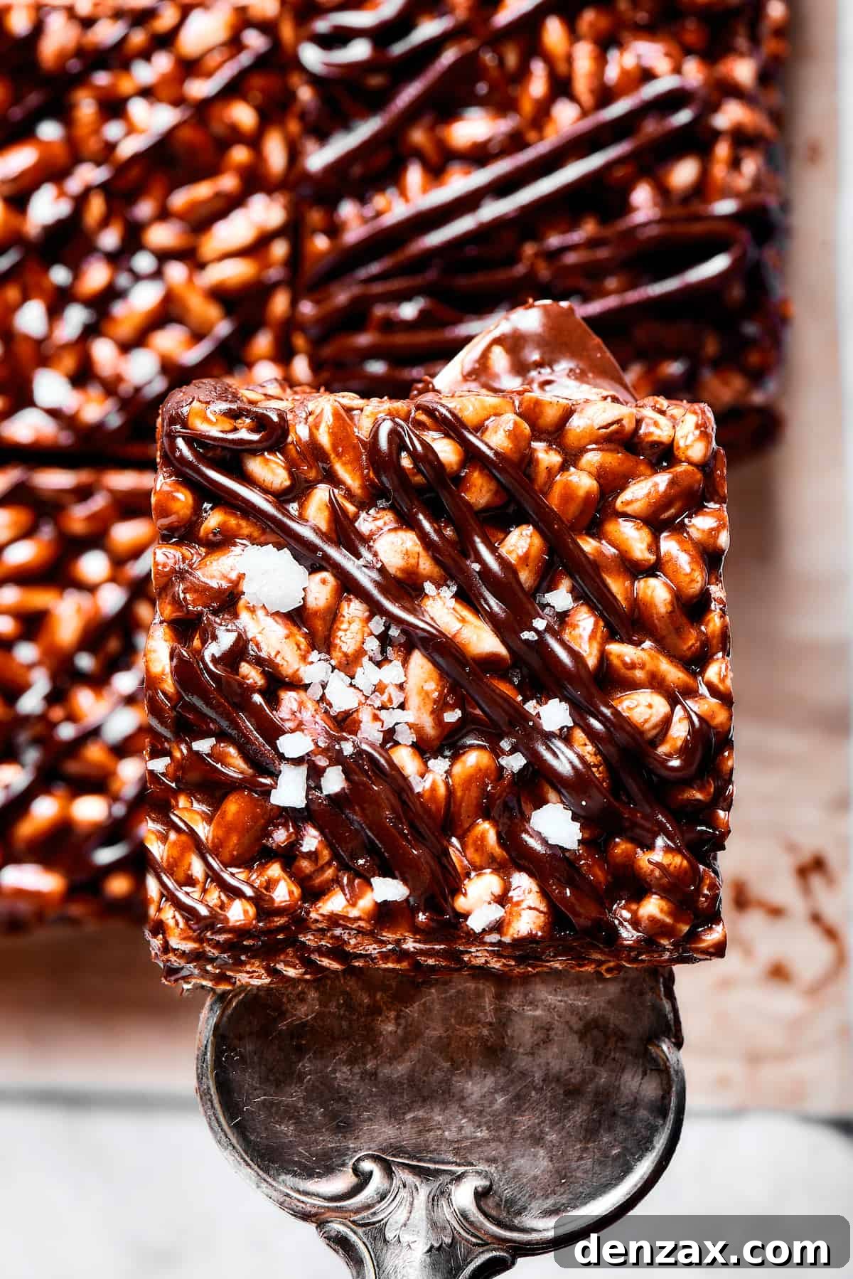 Lifting a chocolate cereal bar square with a silver dessert server.