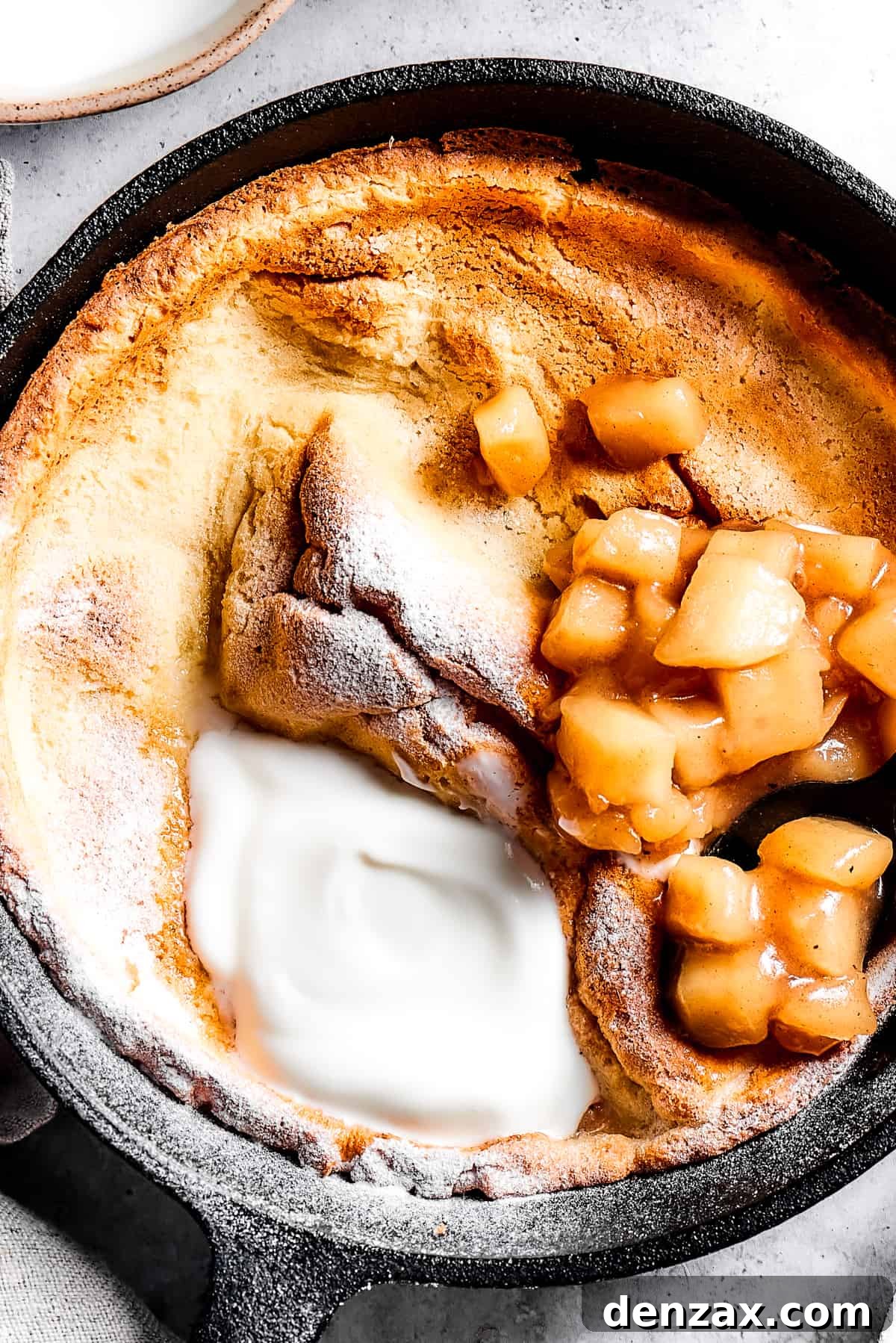 A skillet pancake with apples and creamy topping.