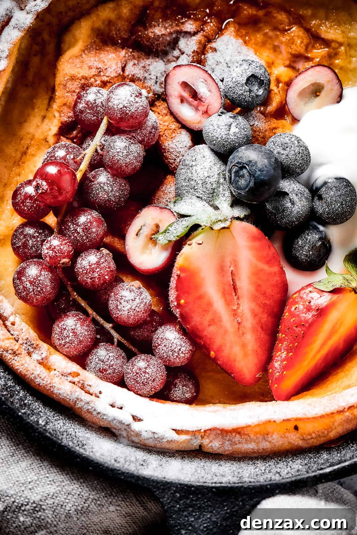 A German pancake topped with powdered sugar and fresh fruit.