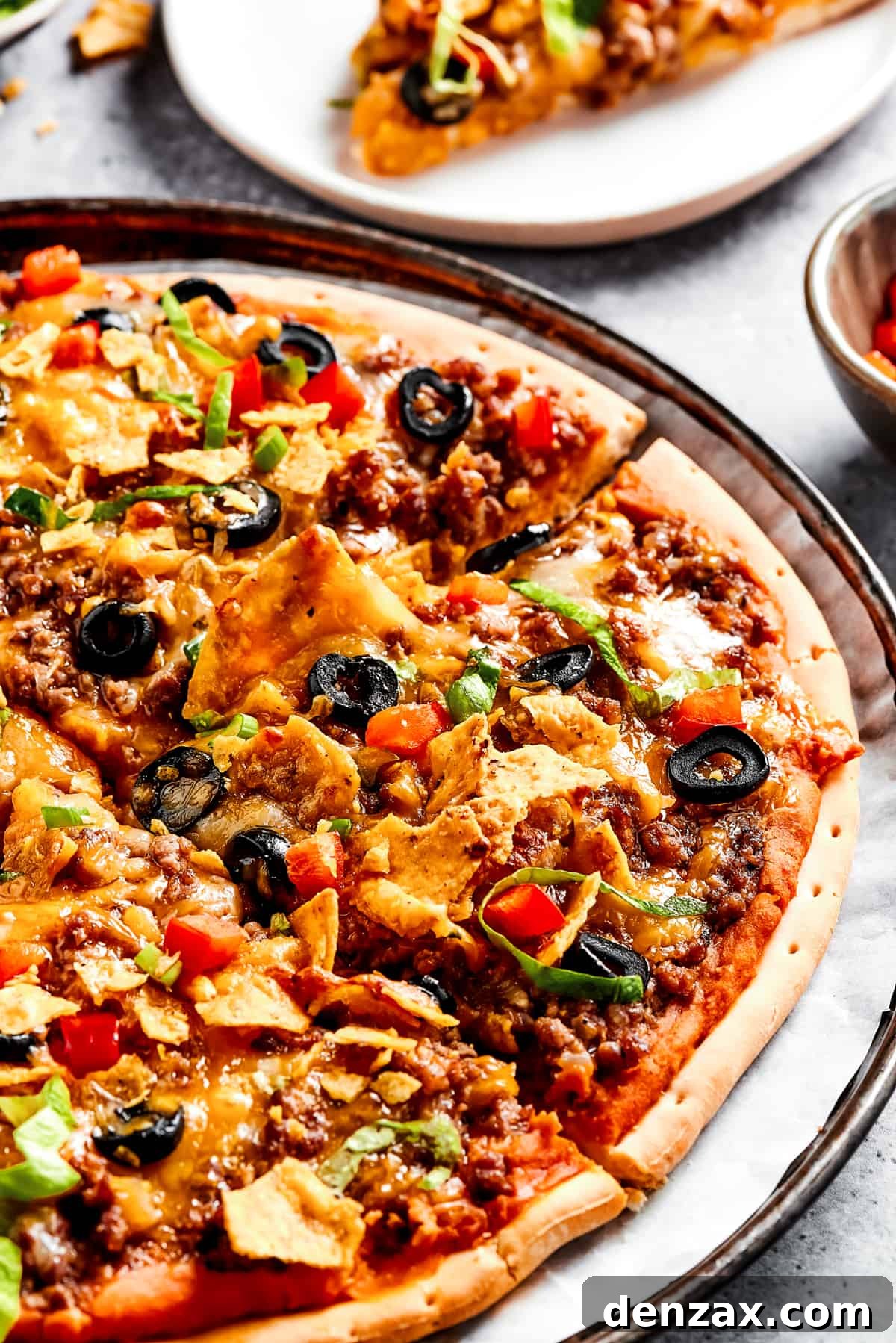 Homemade Mexican pizza with shredded lettuce, crushed tortilla chips, and other toppings.