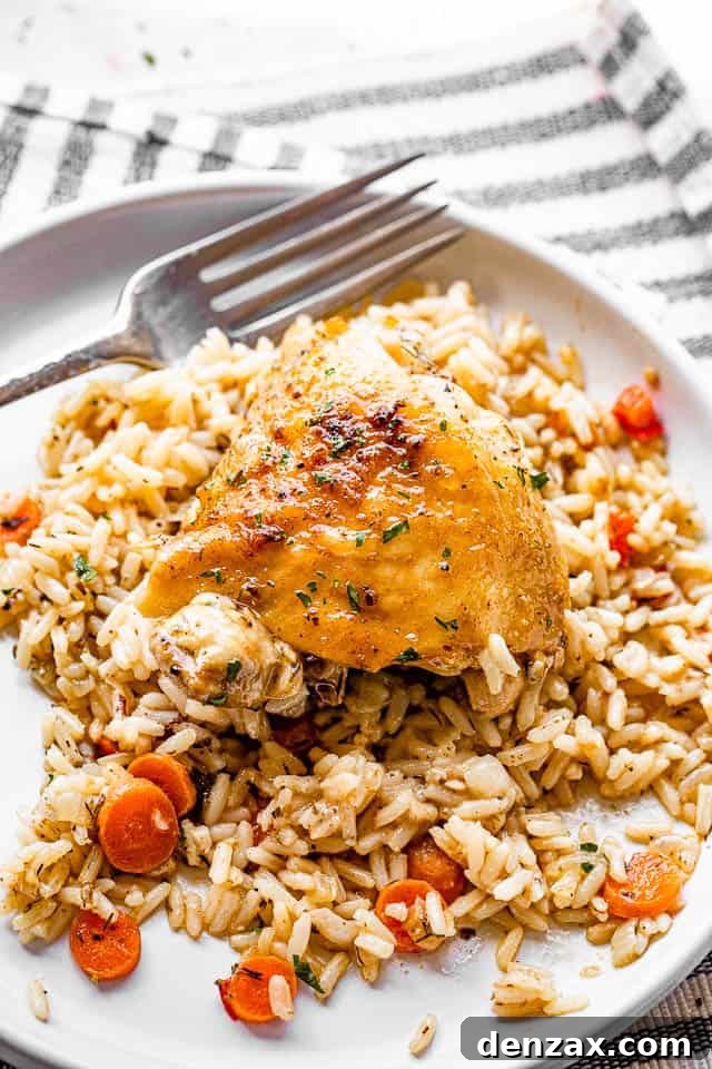 skin-on chicken thighs served over rice in a white plate with fork on the side
