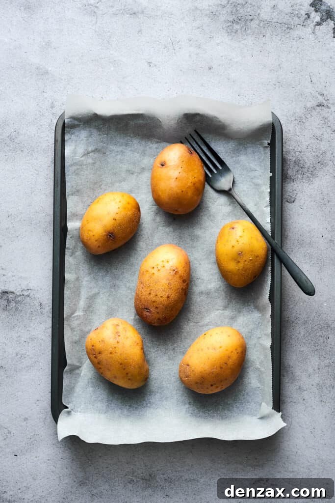 Potatoes washed, pricked with a fork, and arranged on a baking sheet.