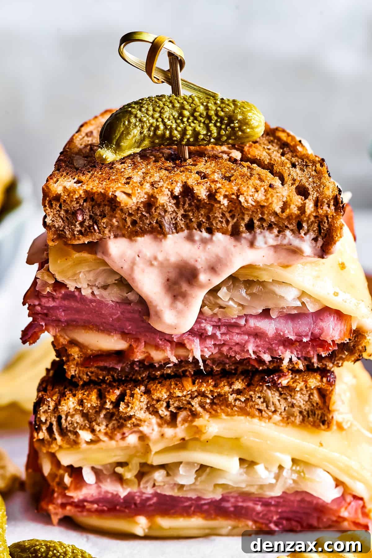Two Reuben sandwich halves with Russian dressing dripping from one.