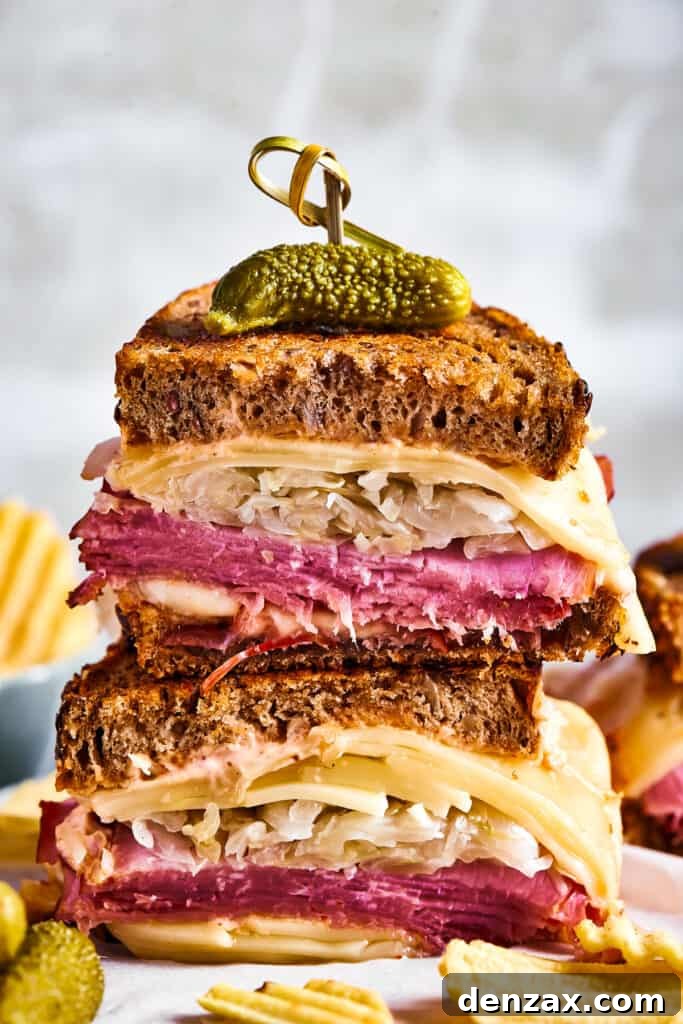 Grilled sandwich halves stacked and topped with a pickle.